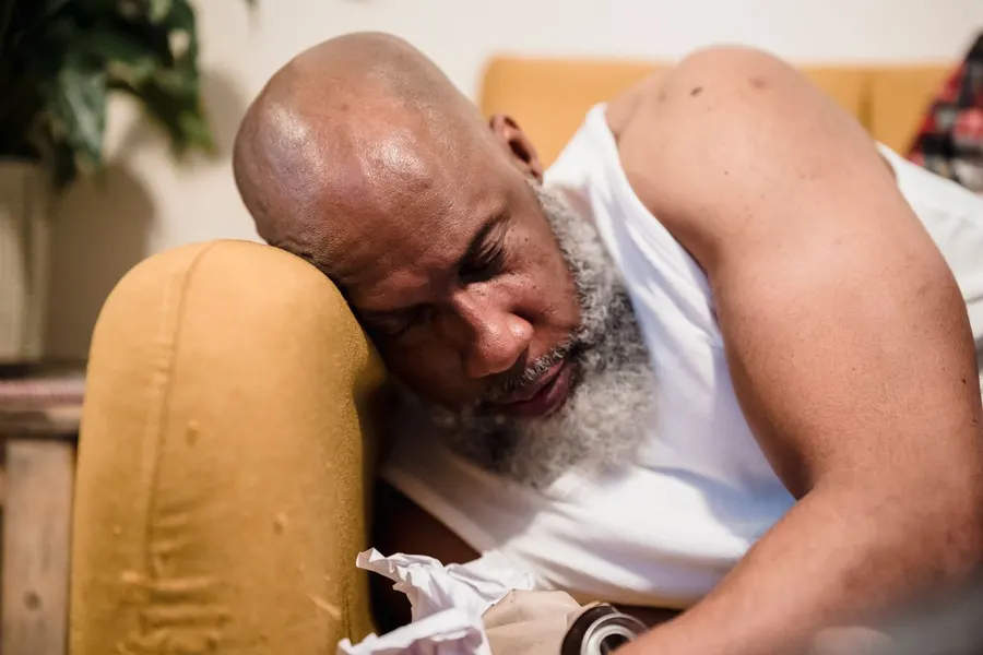 Tired man resting his head on the arm of a couch